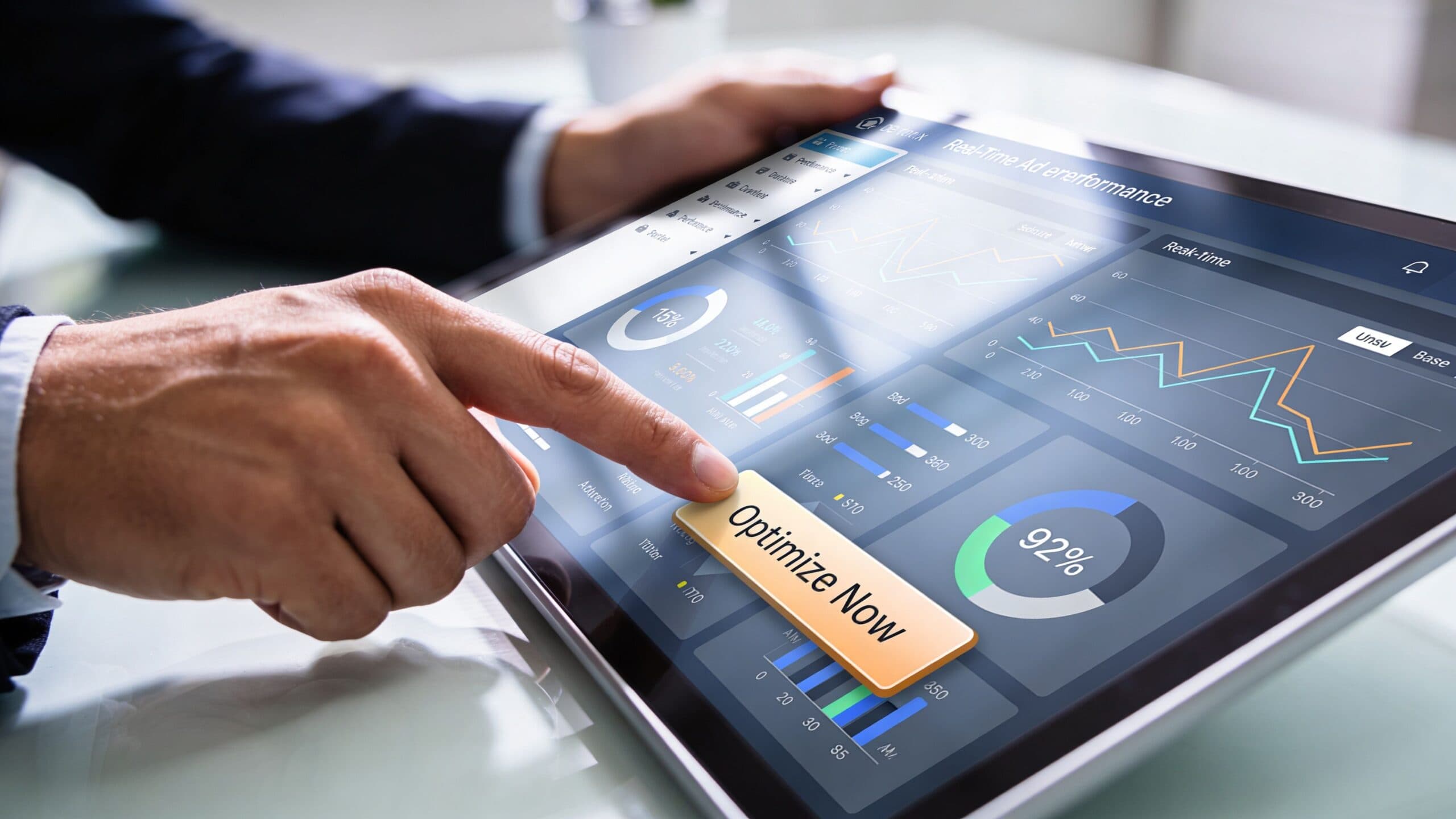 A business professional using a digital tablet to analyze real-time advertisement performance metrics on a dashboard.