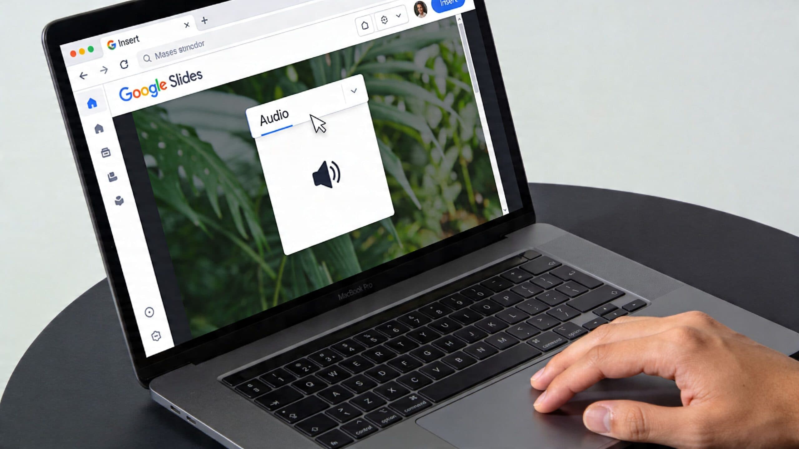 A hand using a laptop to add an audio file into a Google Slides presentation slide.